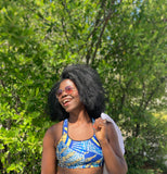 Happy woman in a The Wrapper Ankara print sports bra top standing outdoors with greenery in the background