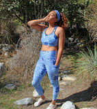Woman standing outdoors with trees and rocks in the background wearing No Wahala Ankara print matching set – leggings with pockets styled with matching sports bra.