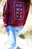 Person wearing a maroon No Wahala Crewneck sweatshirt with hands in Ankara leggings pockets outdoors
