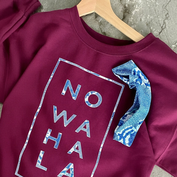 Maroon Ankara print No Wahala crewneck sweatshirt with matching headband on a stone surface