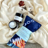 Flat lay of Ankara Lavender Eye Pillow with magnesium lotion jars on cream fabric on a rock for relaxation and sleep